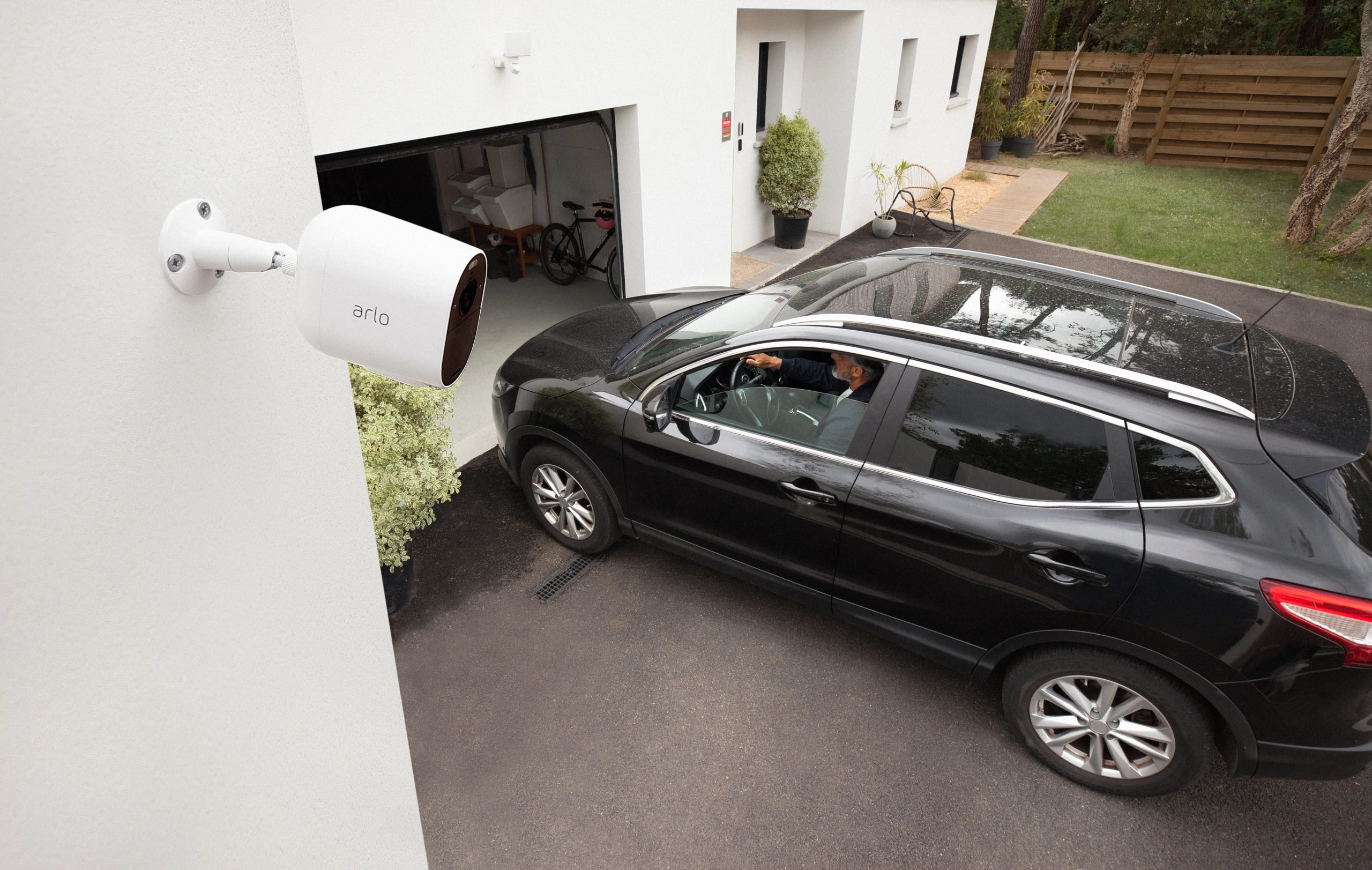 Carro entrando na garagem e câmera de segurança realizando o monitoramento.