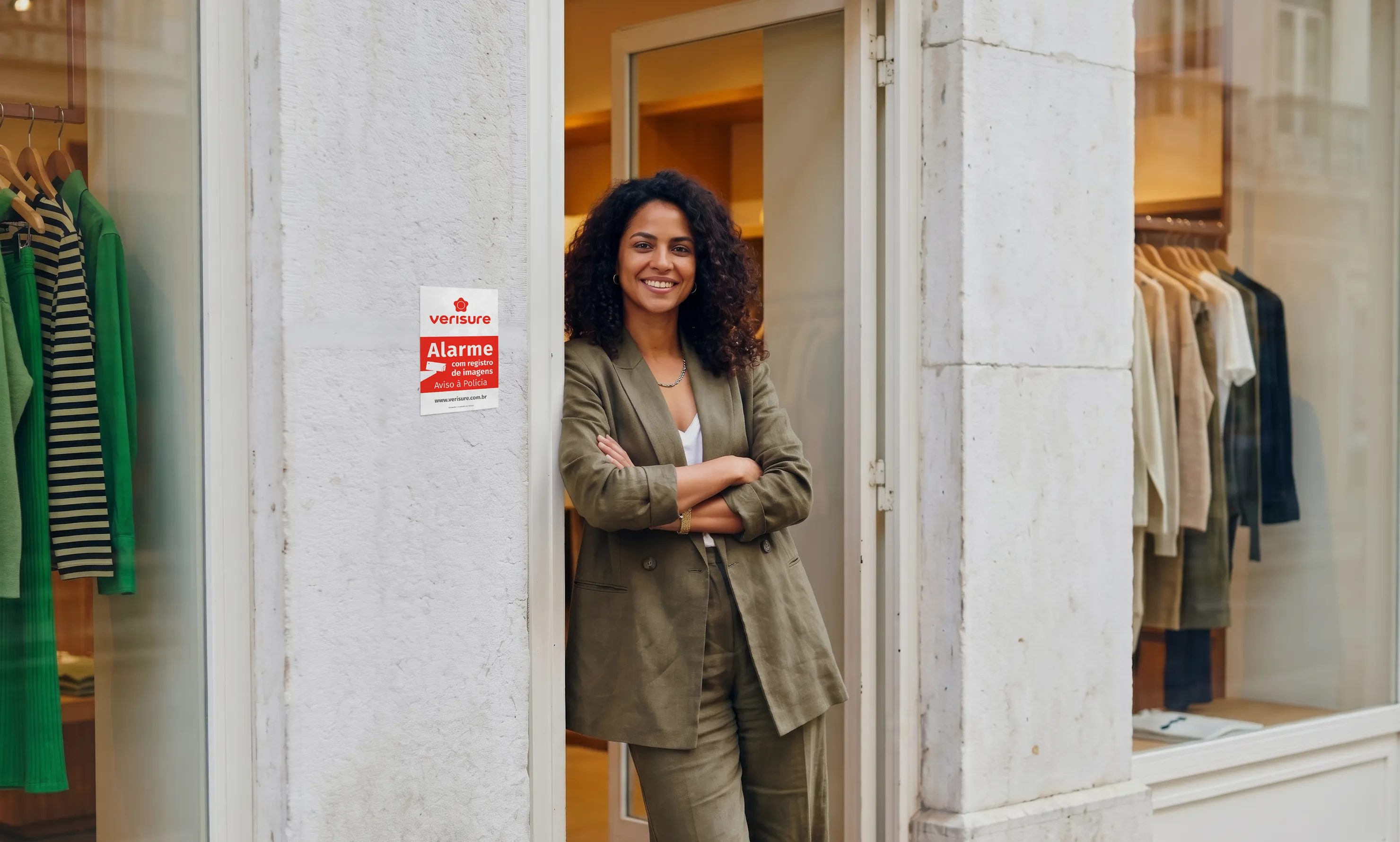 Empreendedora em frente a sua loja ao lado da placa de inibição Verisure