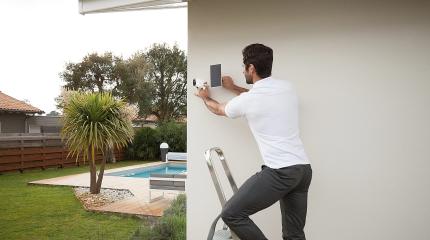 Pessoa realizando instalação de câmera Verisure no ambiente externo da casa.