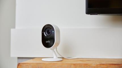 Câmera de segurança inteligente Arlo instalada em mesa de madeira, ideal para monitoramento doméstico e segurança residencial moderna.