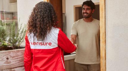 profissional Verisure chegando na casa do cliente, cumprimentando-o na entrada da porta. 