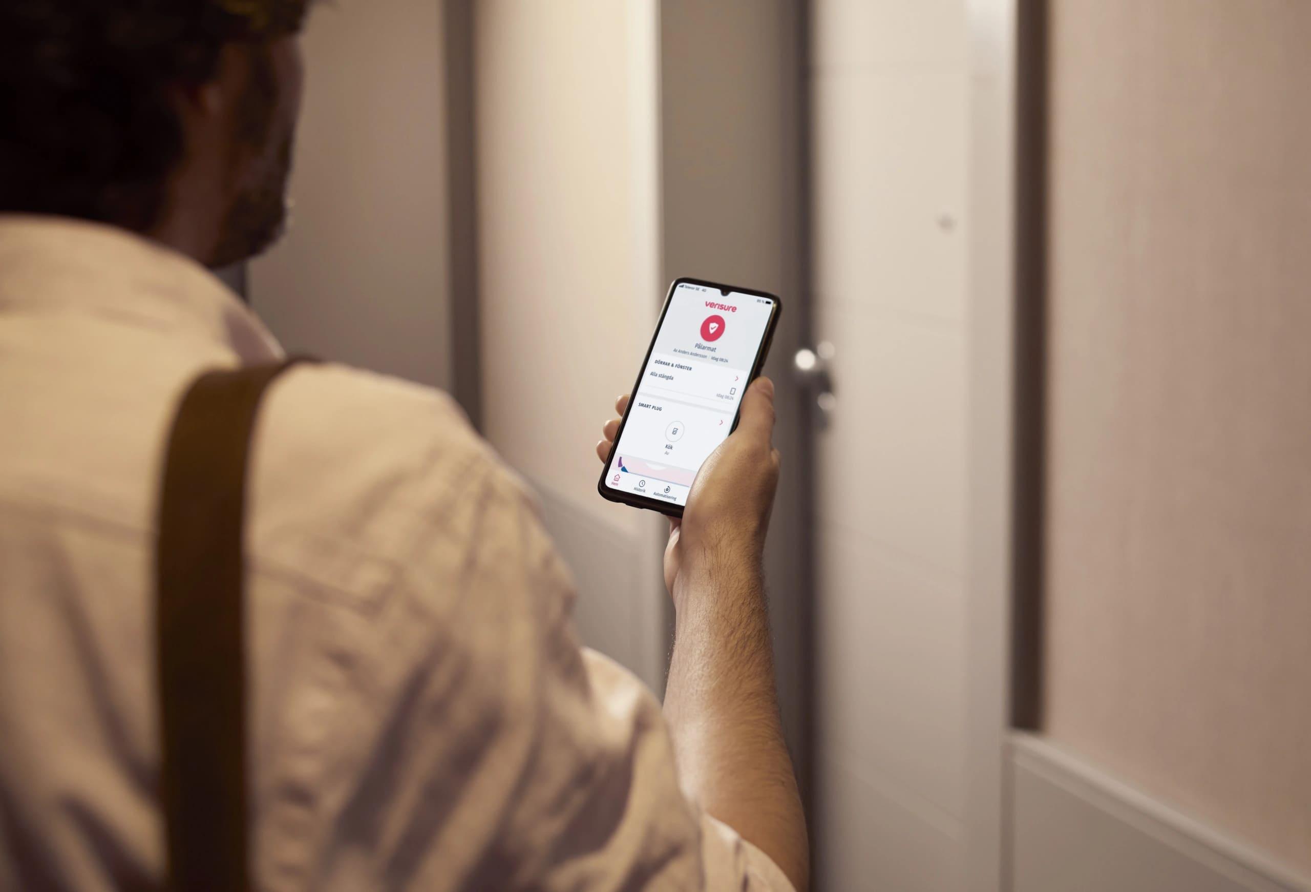 Pessoa usando smartphone para realizar monitoramento com aplicativo Verisure.